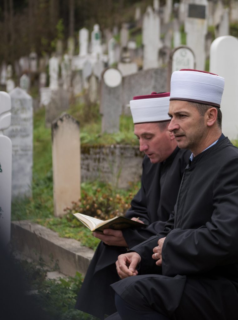 quran holy book reading by imam  on islamic funeral with white thumb stones graweyard background
